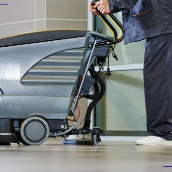 Employé utilisant une autolaveuse industrielle pour nettoyer un plancher commercial, illustrant l’efficacité et la réduction des coûts en entretien ménager.
