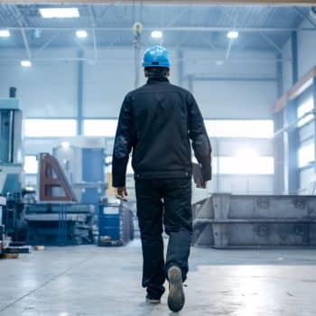 Superviseur d’usine portant un casque inspectant un environnement industriel pour assurer la sécurité et la conformité CNESST