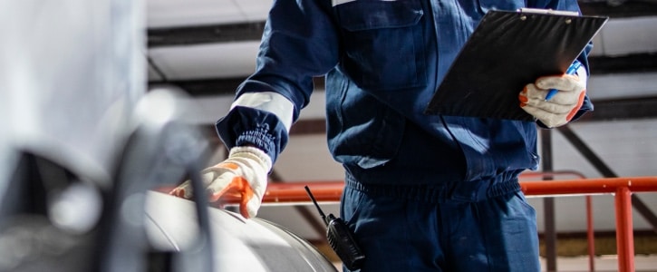 Agent en uniforme effectuant une inspection industrielle avec une tablette, conforme aux Normes de ménage industriel.