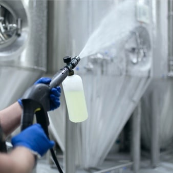 Nettoyage sous pression d’équipements industriels en acier inoxydable, illustrant les bonnes pratiques liées aux Normes de ménage industriel.